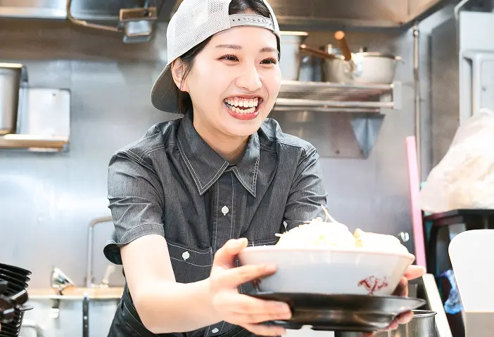 笑顔で厨房で料理を提供するスタッフの様子